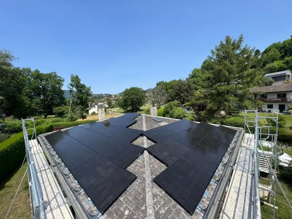 Modules solaires noirs sur le toit en tuiles grises d’une maison individuelle à St-Légier (environs : arbres) – échafaudage encore en place