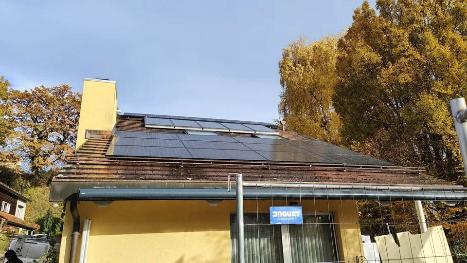 Modules solaires noirs sur le toit en tuiles d’une maison individuelle à Prilly (environs : arbres)