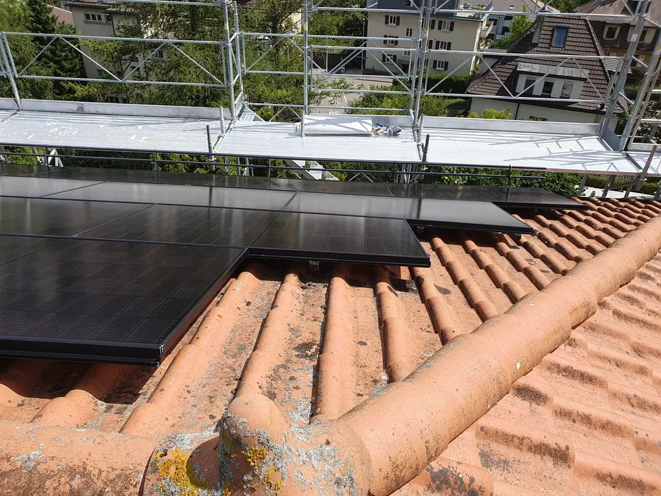 Modules solaires noirs sur le toit en tuiles rouges d’un immeuble à Fribourg (environs : quartier urbain)