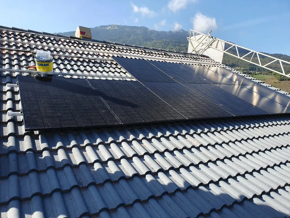 Schwarze Solarmodule auf dem grauen Ziegeldach eines Einfamilienhauses in Monthey (Umgebung: Berge)