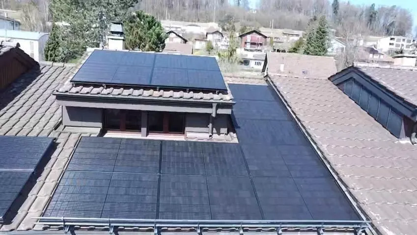 Schwarze Solarmodule auf dem Ziegeldach eines Einfamilienhauses in Matran (Umgebung: Nachbarhäuser)