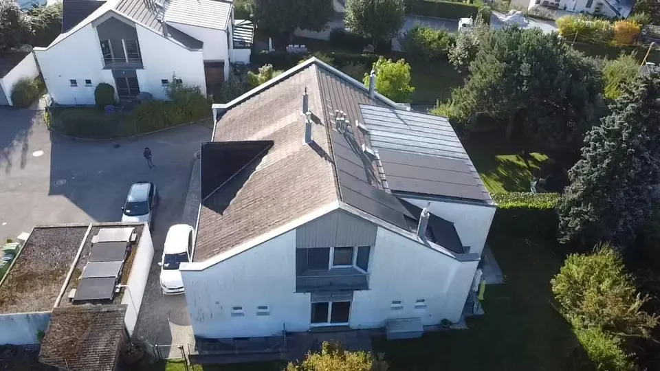 Luftbild: schwarze Solarmodule auf dem grauen Ziegeldach eines Einfamilienhauses in Matran (Umgebung: Garten)