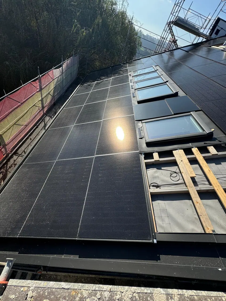 Bauphase: Indach-Module um vier Dachfenster, rechts noch offene Lattung, am Rand das Gerüst