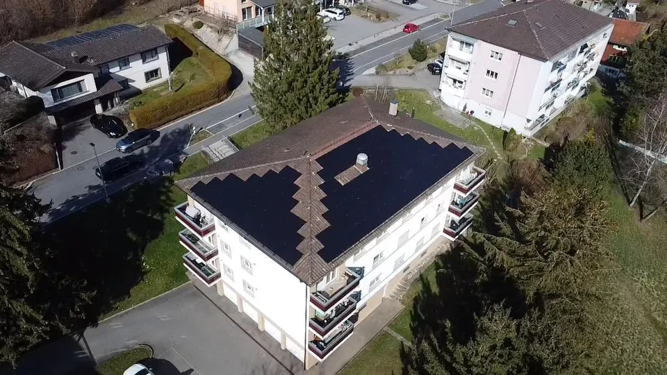 Luftbild: schwarze Solarmodule auf dem dunklen Ziegeldach eines Einfamilienhauses in Matran (Umgebung: Nachbarhäuser) – weitere Ansicht