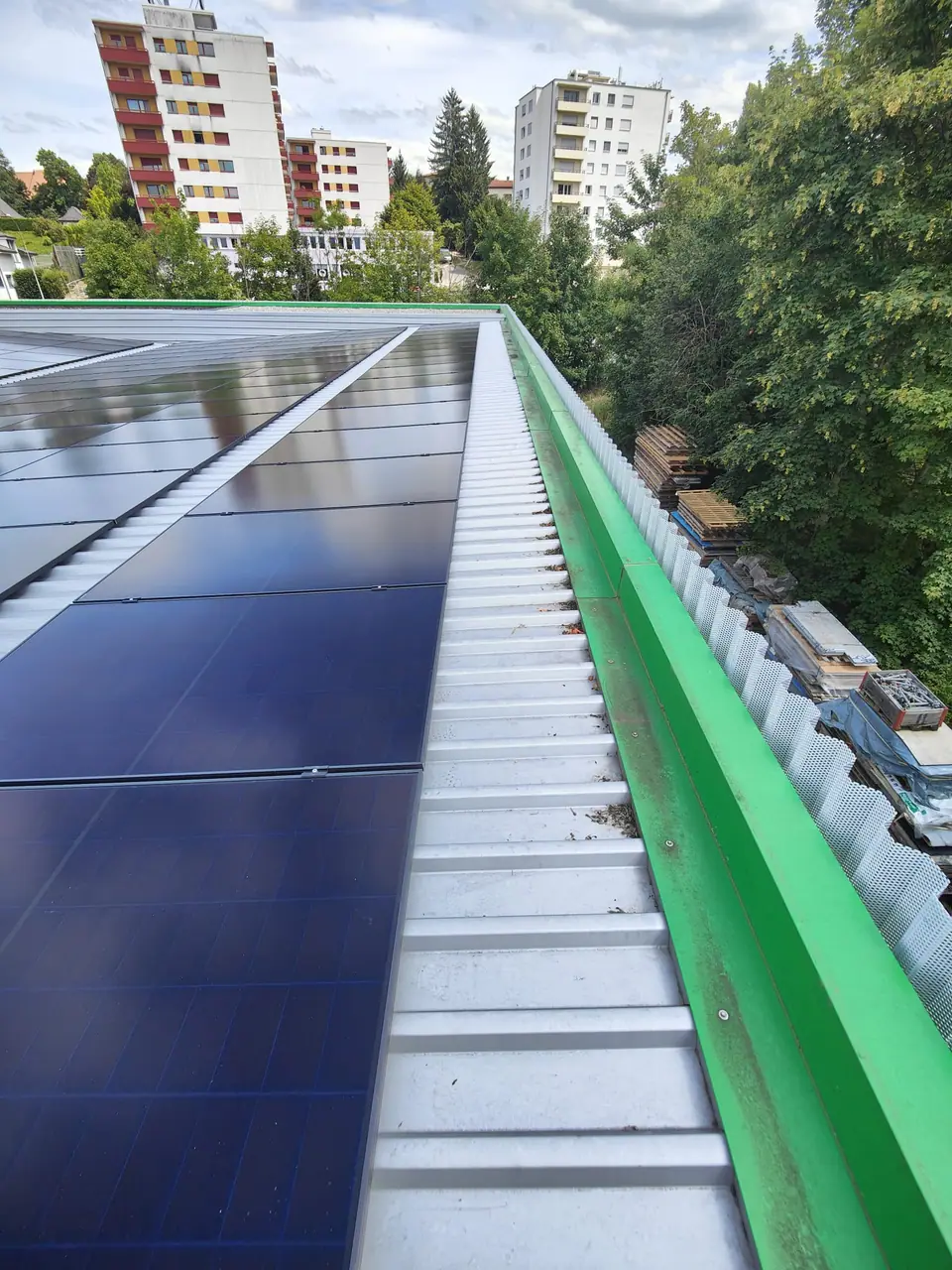 Rangées de modules sur le toit en tôle du bâtiment commercial à Givisiez, immeubles en arrière-plan
