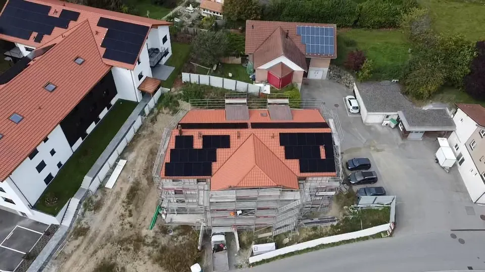 Vue aérienne : modules solaires noirs sur le toit en tuiles rouges d’un immeuble à Cottens (environs : maisons voisines)
