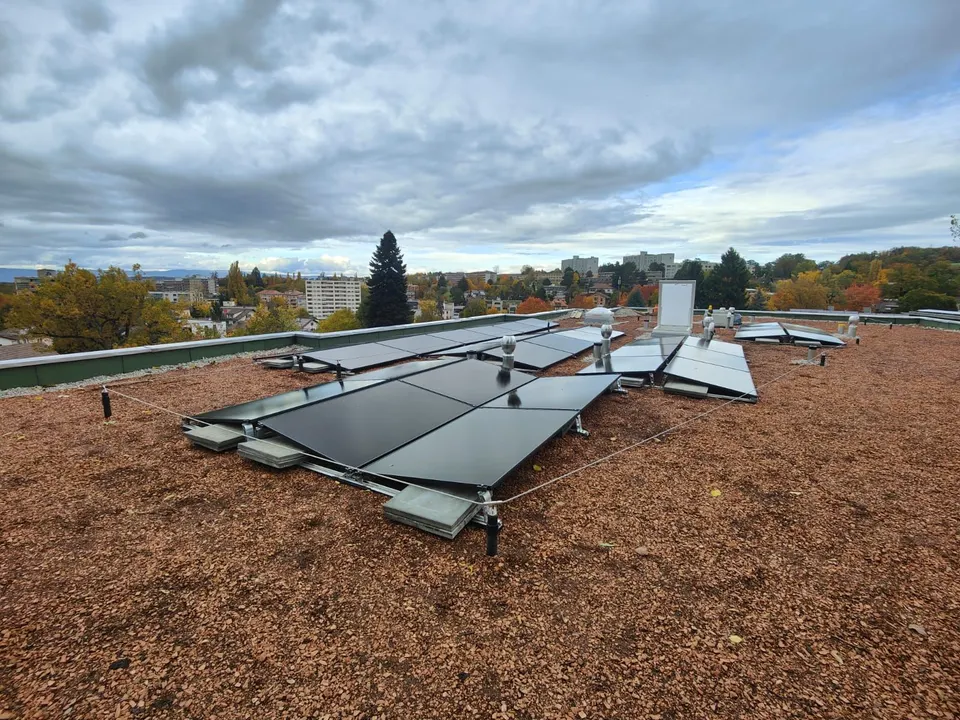 Schwarze Solarmodule auf dem begrünten Flachdach eines neuen Mehrfamilienhauses in Freiburg (Umgebung: Stadtquartier)