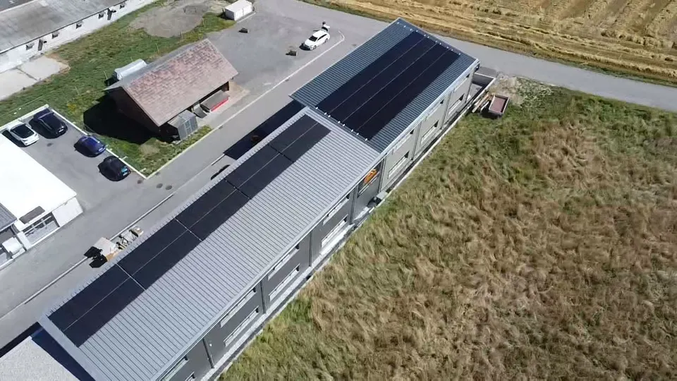 Luftbild: schwarze Solarmodule auf dem Blechdach einer Halle in Cournillens (Umgebung: Wiesen) – weitere Ansicht